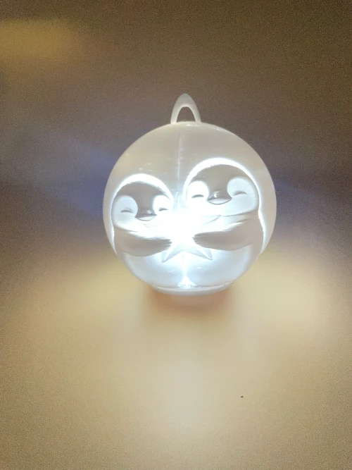 Boule lumineuse décorative imprimée en 3D, motif pingouins, idéale pour Noël ou déco hivernale.