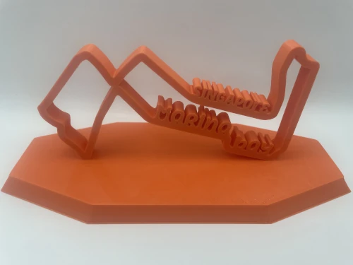 Sculpture décorative imprimée en 3D représentant le tracé du circuit de Marina Bay (Singapour), sur socle octogonal orangé.