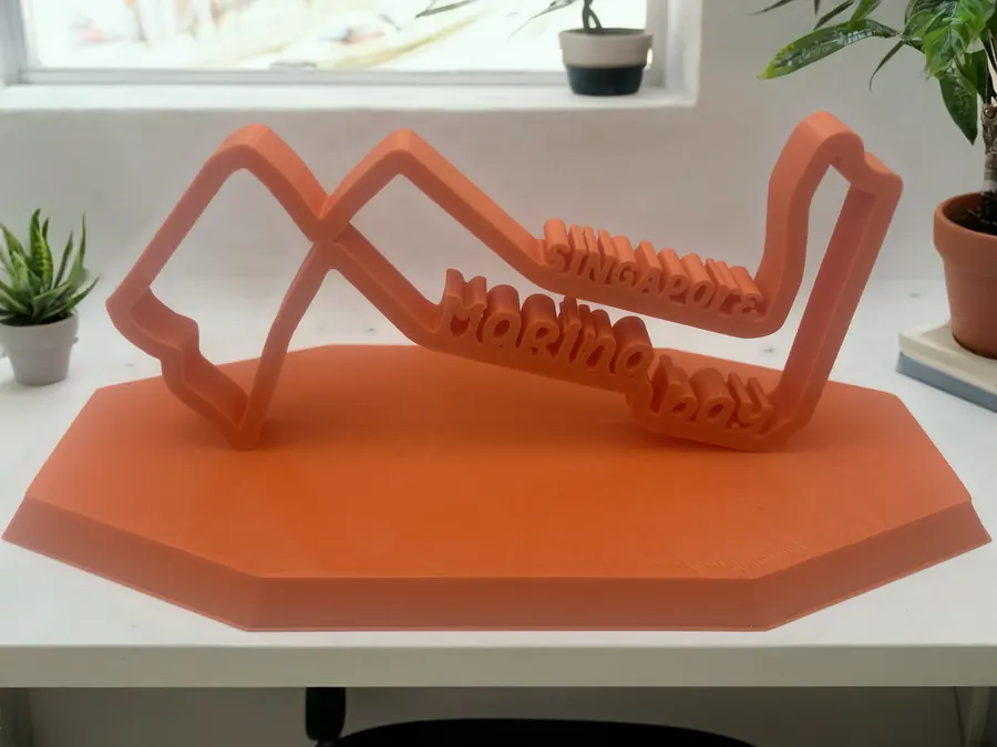 Sculpture décorative imprimée en 3D représentant le tracé du circuit de Marina Bay (Singapour), sur socle octogonal orangé.