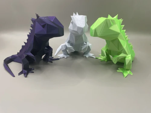 Set de sculptures 3D style low-poly représentant trois lézards/iguane en violet, blanc et vert.