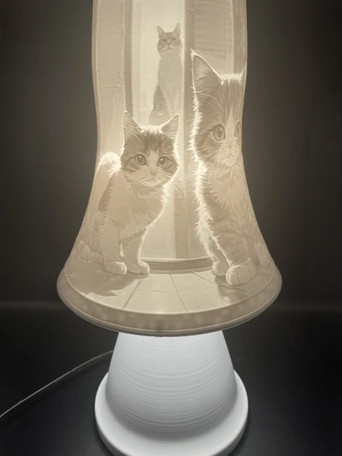 Lampe décorative en lithophanie représentant des chats, posée sur un socle blanc, éclairage chaleureux.