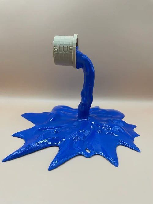 Sculpture imprimée en 3D représentant un pot de peinture renversé formant une éclaboussure bleue.