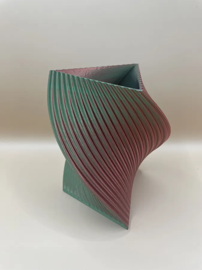 Vase décoratif imprimé en 3D, forme torsadée triangulaire, style moderne et coloré.
